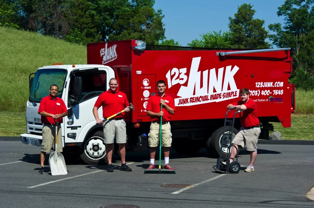 Four workers in red shirts standing in front of a 123JUNK truck with cleaning tools