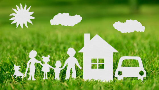 Paper-cut style graphic of a family, house, car, sun, and clouds set against a green grass background