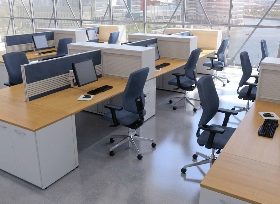 Modern open-plan office with rows of wooden desks, blue swivel chairs, and computer monitors, overlooking a river through large windows