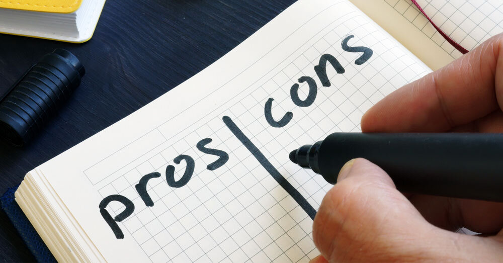 Close-up of a notebook page with the words “pros” and “cons” written in bold black marker, divided by a vertical line
