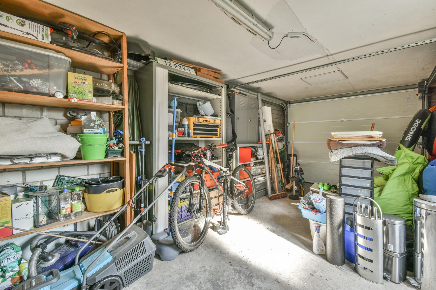 A garage with bicycles and tools, divided into four labeled zones on the floor for decluttering